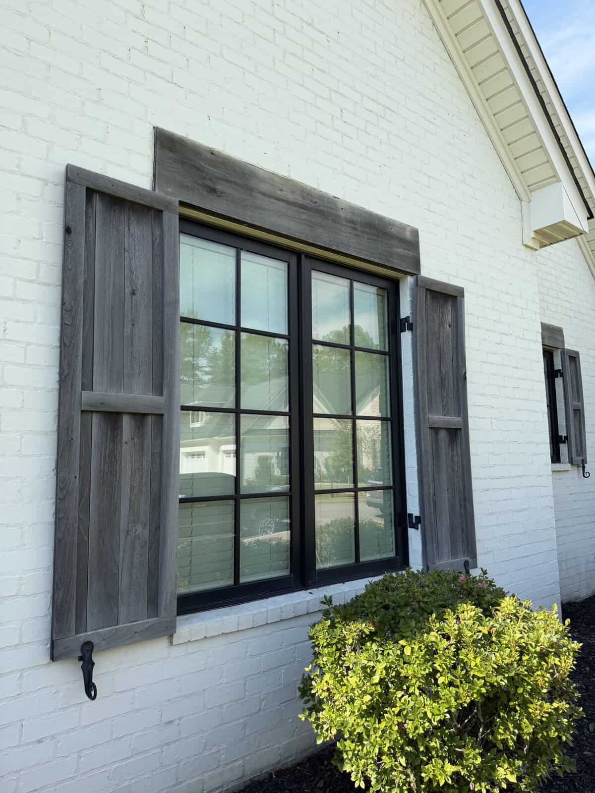 Black framed windows and wood shutters against freshly painted white brick