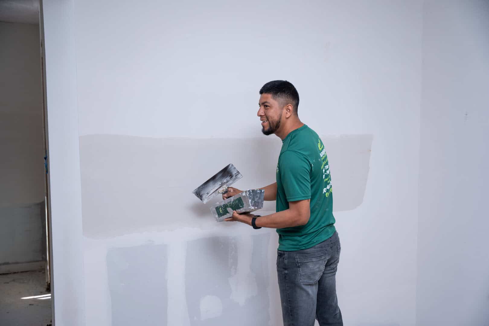 Amaya G Painting technician smoothing joint compound over a drywall seam with a taping knife