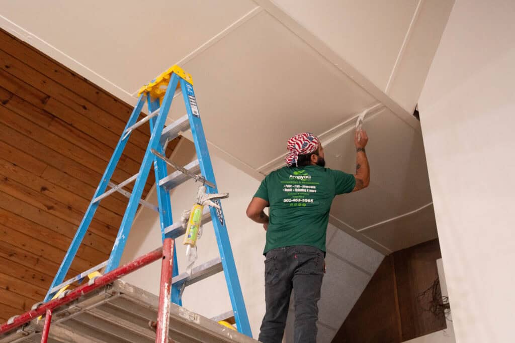 Amaya G Painting painter cutting in a vaulted interior wall from a ladder